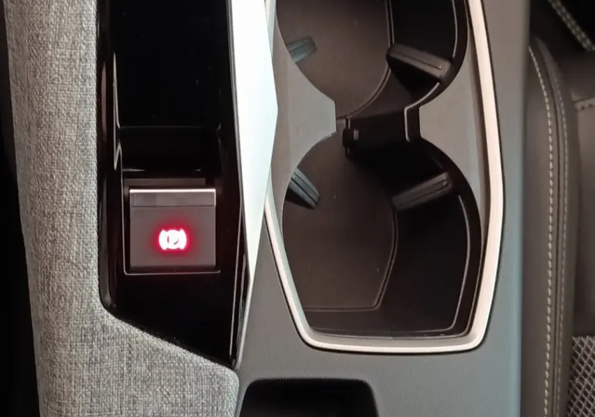 Gros plan sur la console centrale grise du Peugeot 5008 2026 avec porte-gobelets et bouton frein électrique rouge allumé.