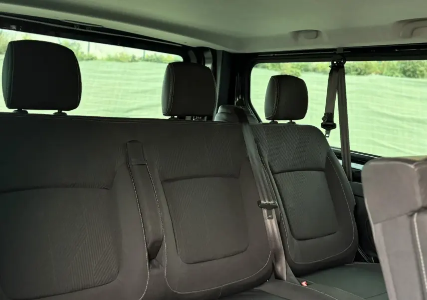 Vue intérieure des sièges arrière noirs du Nissan Primastar Combi L2 3T 2.0 DCI 150 Tekna 2025 avec ceintures visibles.