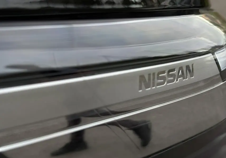 Gros plan sur la calandre noire métallisée du Nissan Primastar Combi avec logo Nissan en relief.