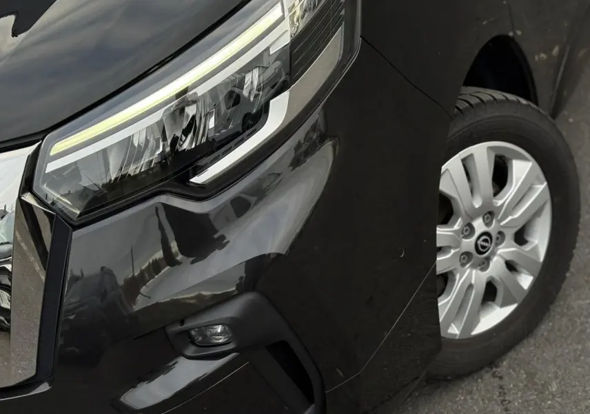 Gros plan sur l'avant droit noir métallisé du Nissan Primastar Combi, mettant en valeur le phare LED et la jante alliage.