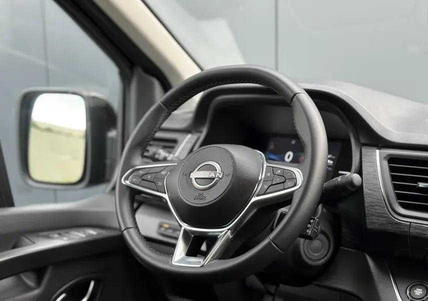 Volant Nissan noir avec commandes intégrées, tableau de bord et rétroviseur côté gauche du Primastar Combi 2025.