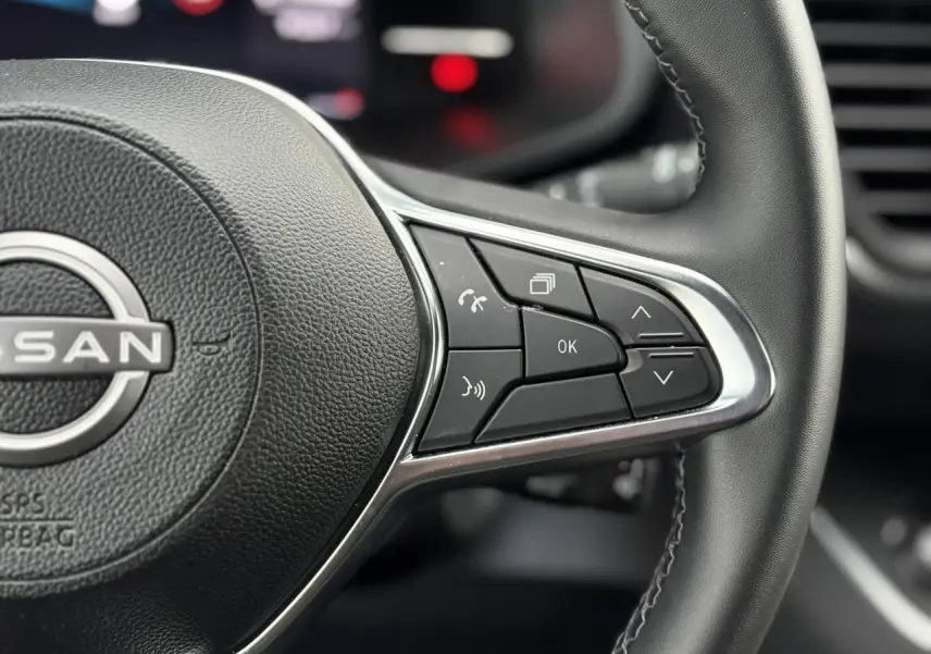 Gros plan sur les commandes multifonctions du volant noir du Nissan Primastar Combi 2025, finition Tekna.