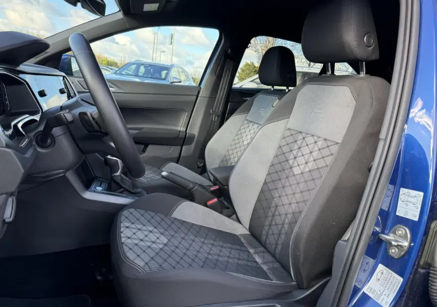 Vue intérieure côté conducteur du Volkswagen Taigo bleu récif, sièges Sport-Confort avec logo R et tissu à motif géométrique.
