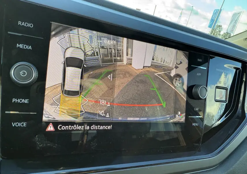 Écran de caméra de recul du Volkswagen Taigo 2025 montrant l'aide au stationnement arrière en extérieur.
