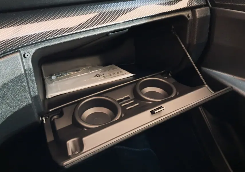 Intérieur de la boîte à gants ouverte de l'AIXAM AMBITION 0.5 CITY COUPE GTI 2026, avec porte-gobelets intégrés.