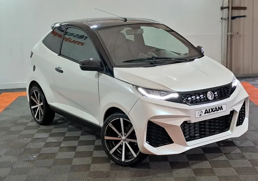 Vue 3/4 avant droite de l'AIXAM AMBITION 0.5 CITY COUPE GTI blanche avec toit noir et jantes sport noires.