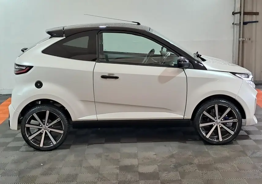 Vue de profil côté gauche d'une AIXAM AMBITION 0.5 CITY COUPE GTI blanche avec rétroviseur caméra côté conducteur.