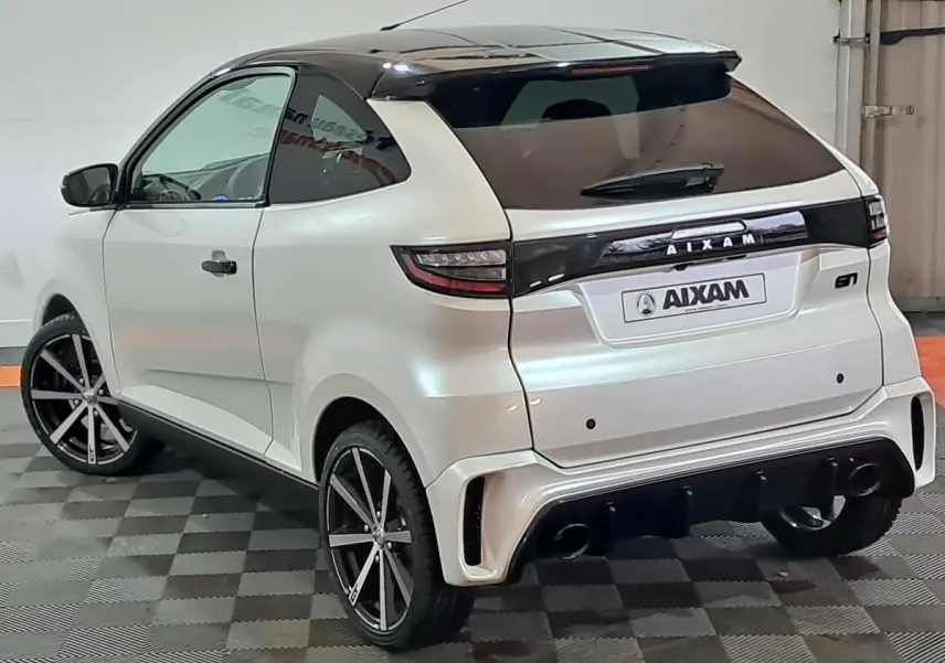 Vue 3/4 arrière gauche d'une AIXAM Ambition 0.5 City Coupe GTI blanche avec toit noir et jantes sport.