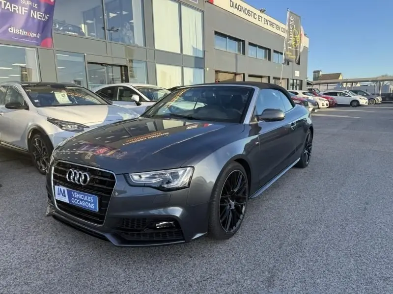 Audi A5 Cabriolet gris métal vue 3/4 avant droit, capote noire et jantes alliage noires distinctives.