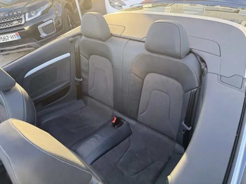 Vue intérieure arrière des sièges en cuir noir de l'Audi A5 Cabriolet gris métal, version S-Line 2016, toit ouvert.