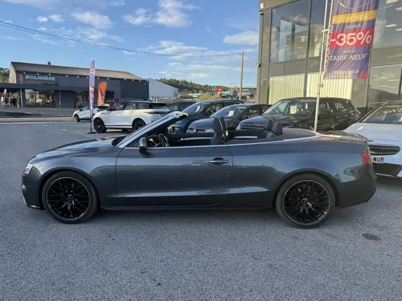 Audi A5 Cabriolet gris métal vue de profil côté gauche, capote ouverte et jantes noires distinctives.