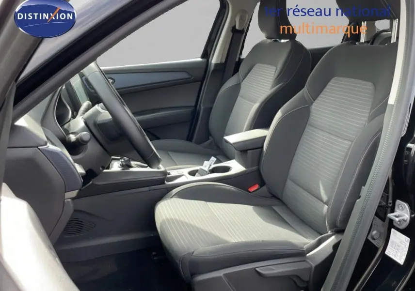 Vue intérieure côté conducteur de la Renault Arkana 2024 noir métal, sièges tissu gris avec console centrale et volant multifonction.