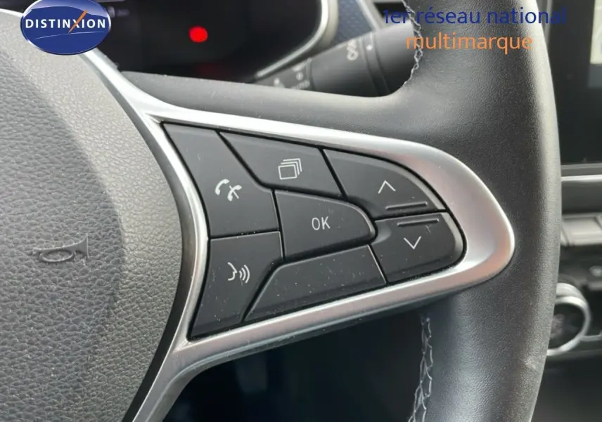 Gros plan sur les commandes au volant en cuir noir du Renault Arkana 2024, version hybride essence, avec boutons multifonctions.