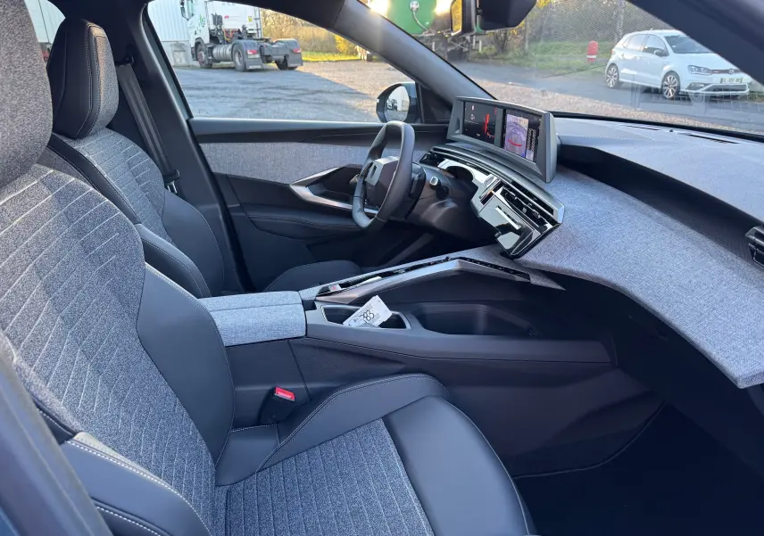 Vue intérieure côté conducteur du Peugeot 3008 Hybrid 2025, avec sièges gris tissu et cuir, tableau de bord moderne et écran digital.