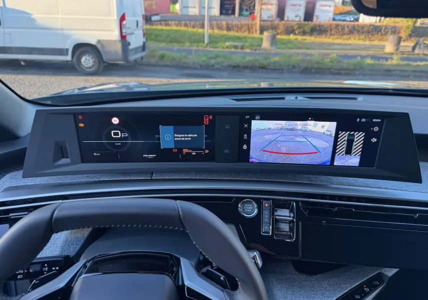 Vue intérieure du tableau de bord du Peugeot 3008 Hybrid 2025 avec écran numérique et caméra de recul affichée.