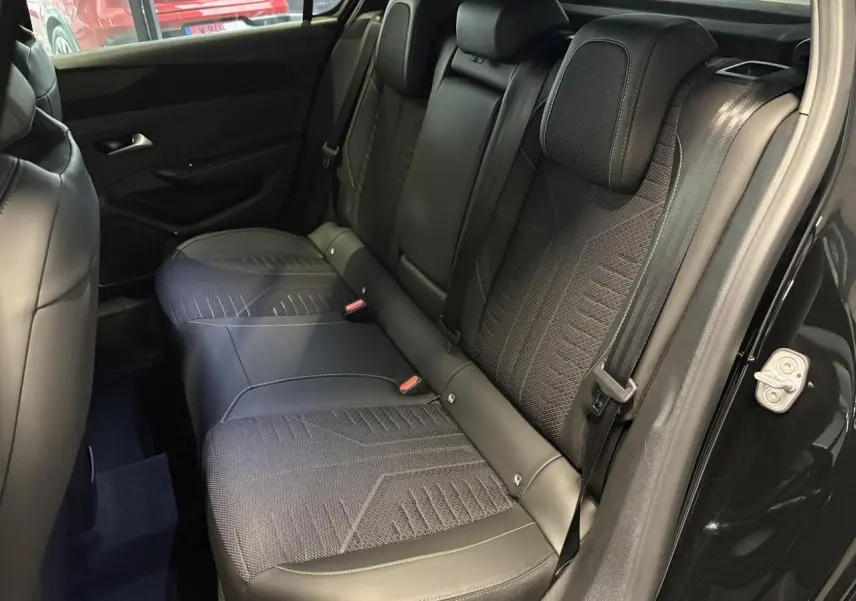Vue intérieure côté droit montrant la banquette arrière tissu et similicuir noir avec surpiqûres vert Adamite sur Peugeot 308 GT 2026.