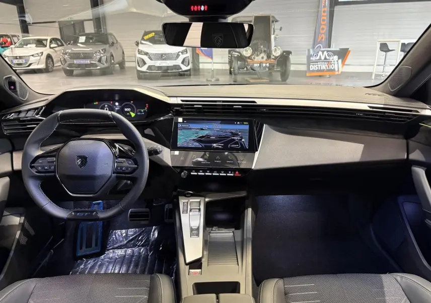 Vue intérieure avant de la Peugeot 308 2026 noire, avec tableau de bord numérique et écran tactile central.