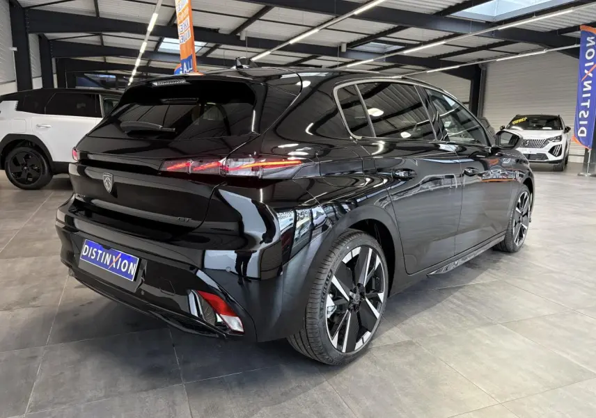 Vue 3/4 arrière droite d'une Peugeot 308 GT noire métallisée avec jantes alliage bi-tons et feux arrière LED 3 griffes.