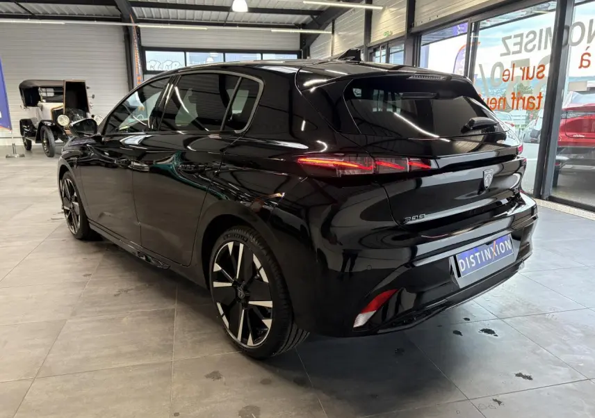 Vue 3/4 arrière droite d'une Peugeot 308 GT noire métallisée avec jantes alliage bi-tons et feux arrière LED distinctifs.