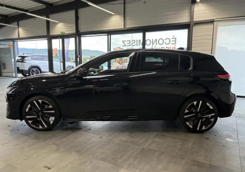 Peugeot 308 noir métallisé vue de profil côté gauche, avec jantes alliage bi-tons et blason sur aile avant.