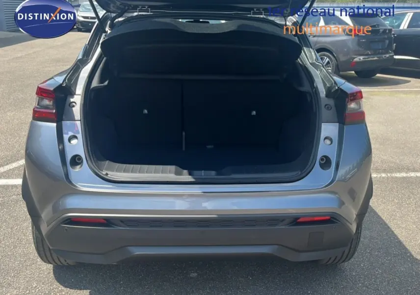 Vue arrière d’un Nissan Juke Hybrid gris squale métal avec coffre ouvert, soulignant son espace de chargement.