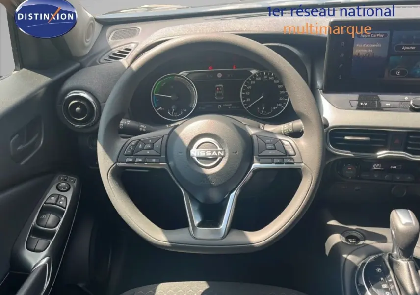 Vue intérieure centrée sur le volant Nissan du Juke Hybrid 2025, avec tableau de bord numérique et console centrale visible.