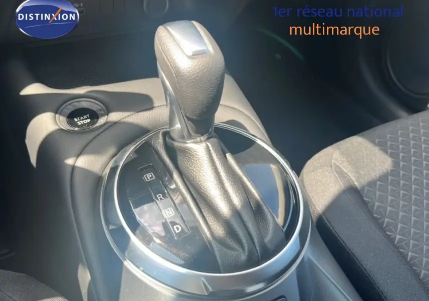 Le levier de vitesses automatique noir du Nissan Juke Hybrid 2025, avec bouton start/stop et siège tissu gris visible.
