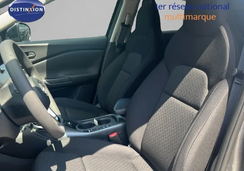Vue intérieure côté conducteur du Nissan Juke Hybrid 2025, sièges tissu gris et volant multifonction.