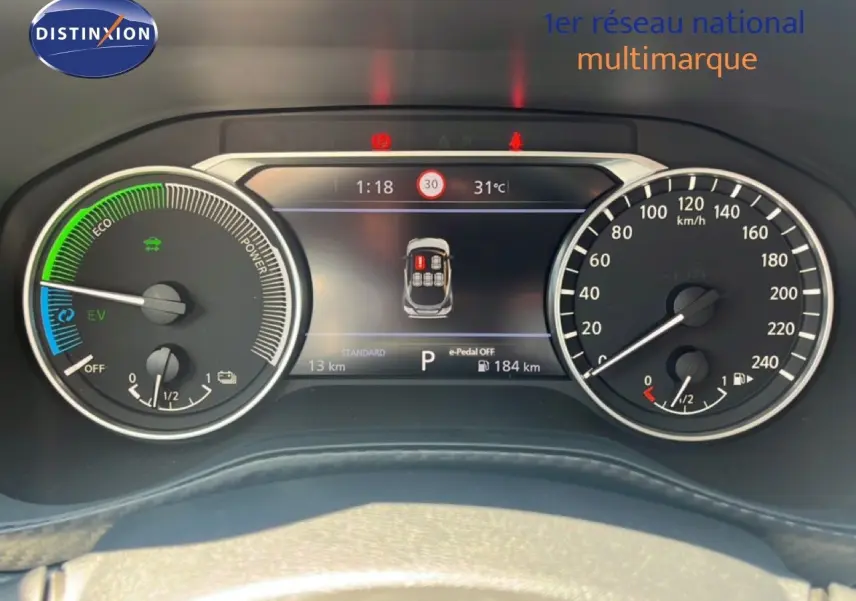 Vue rapprochée du tableau de bord numérique du Nissan Juke Hybrid gris, affichant la vitesse, autonomie et indicateurs hybrides.