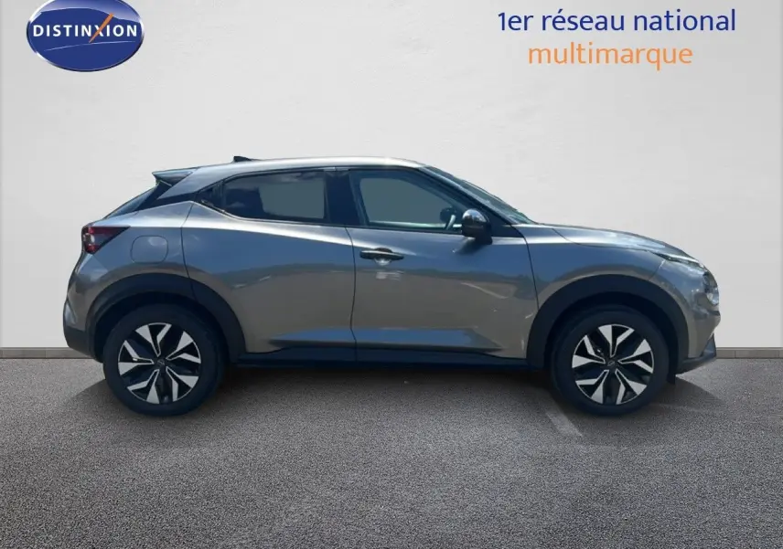 Vue de profil côté gauche d’un Nissan Juke Hybrid 2025 gris squale métal avec jantes distinctives noires et argentées.