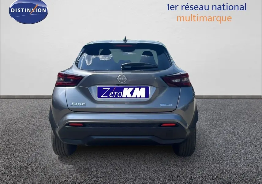 Vue arrière d'un Nissan Juke gris squale métal 2025 avec logo Hybrid et plaque Zéro KM visible sur fond neutre.