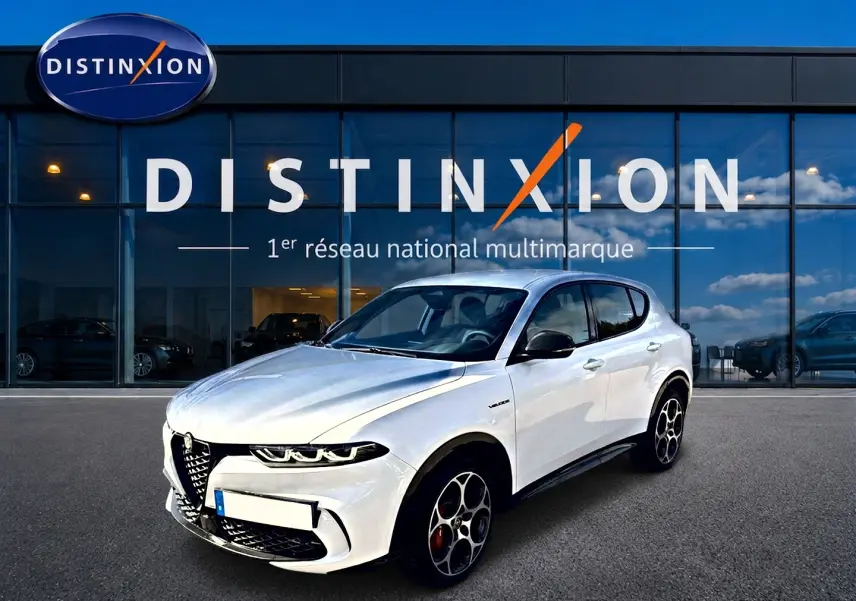 Vue 3/4 avant d'une Alfa Romeo Tonale blanche avec jantes spécifiques et calandre caractéristique, devant une vitrine Distinxion.