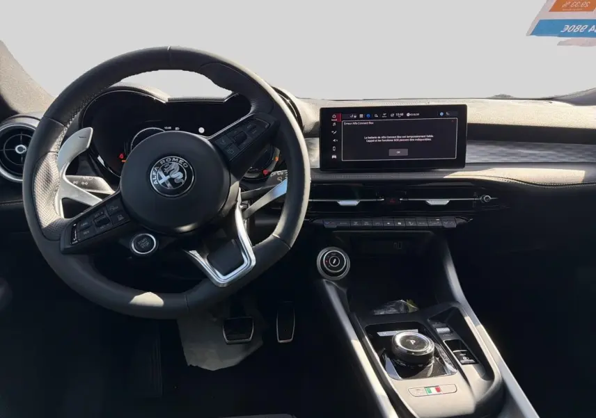 Vue intérieure de face du poste de conduite de l'Alfa Romeo Tonale 2025 avec volant cuir et écran tactile central.