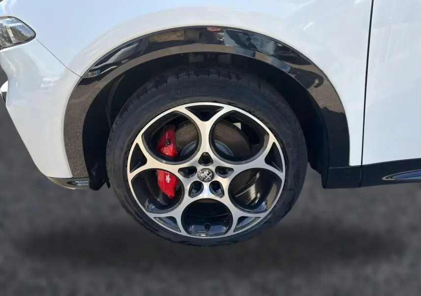 Gros plan sur la roue avant gauche blanche d'Alfa Romeo Tonale avec jante alu et étrier de frein rouge.