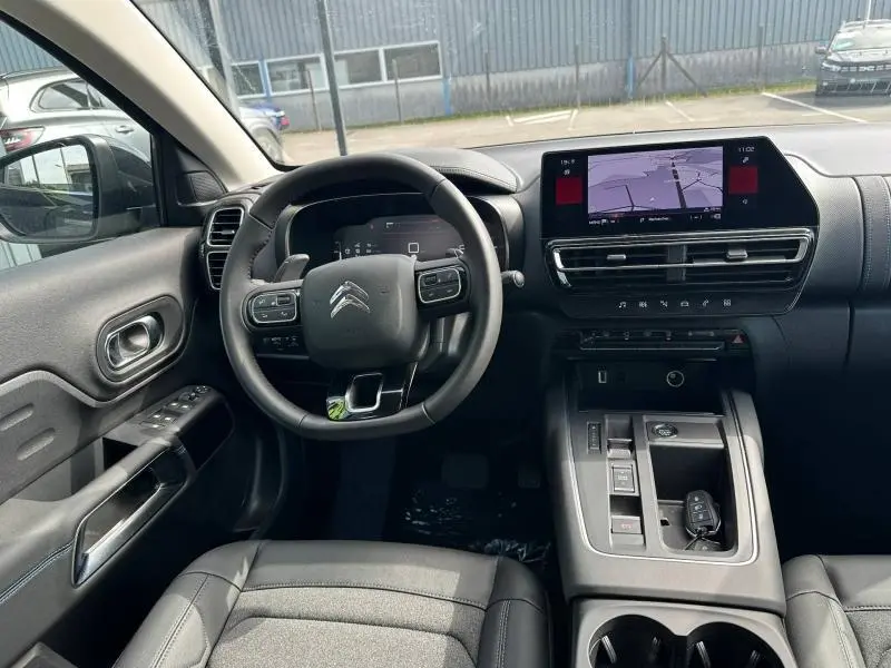 Vue intérieure du poste de conduite du Citroën C5 Aircross 2025 noir, avec volant multifonction et écran tactile central.