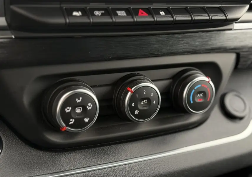 Gros plan sur les commandes de climatisation du Nissan Primastar Combi 2025, boutons noirs avec réglages ventilation et air conditionné.