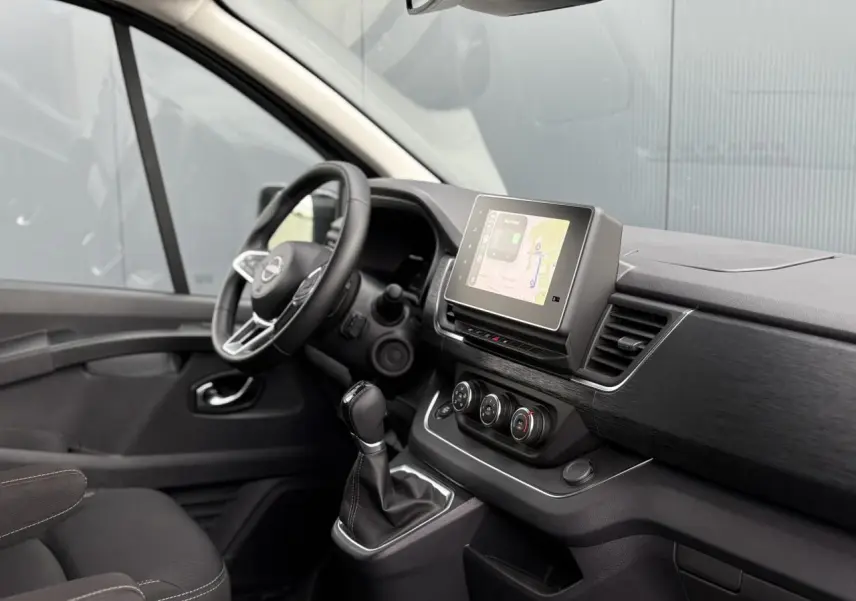 Intérieur du Nissan Primastar Combi 2025 vu côté conducteur, avec tableau de bord noir et écran tactile central.