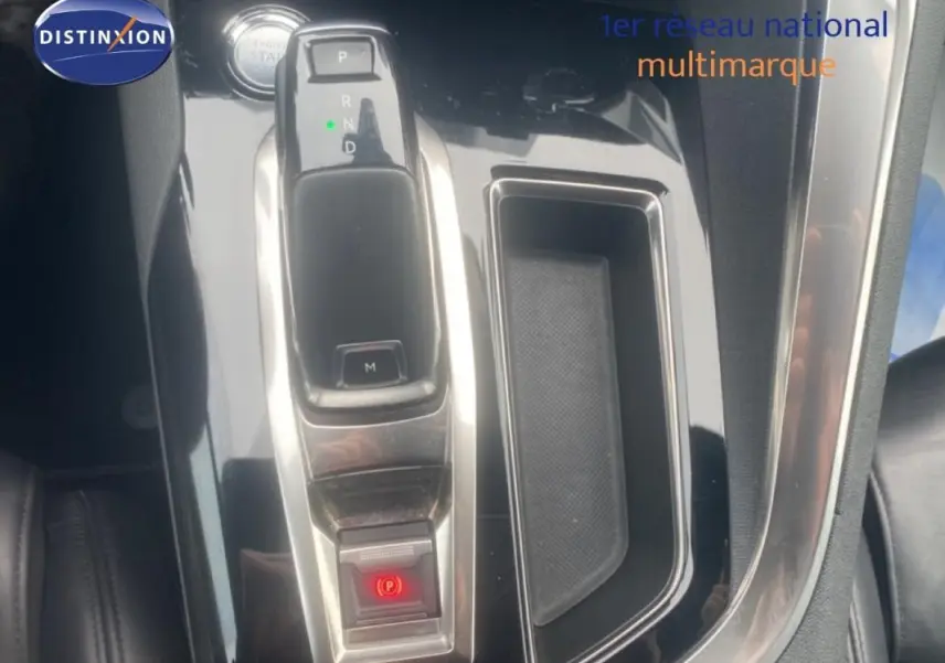 Gros plan sur la console centrale du Peugeot 3008 blanc, mettant en valeur le levier de vitesse automatique et le frein à main électronique.