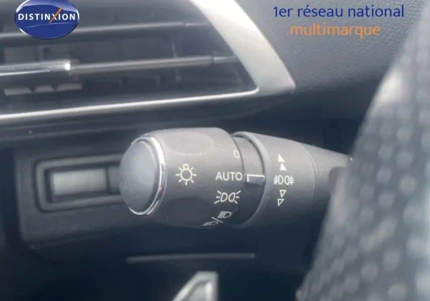 Gros plan sur la commande des phares du Peugeot 3008 blanc, avec tableau de bord et aérateur en arrière-plan.