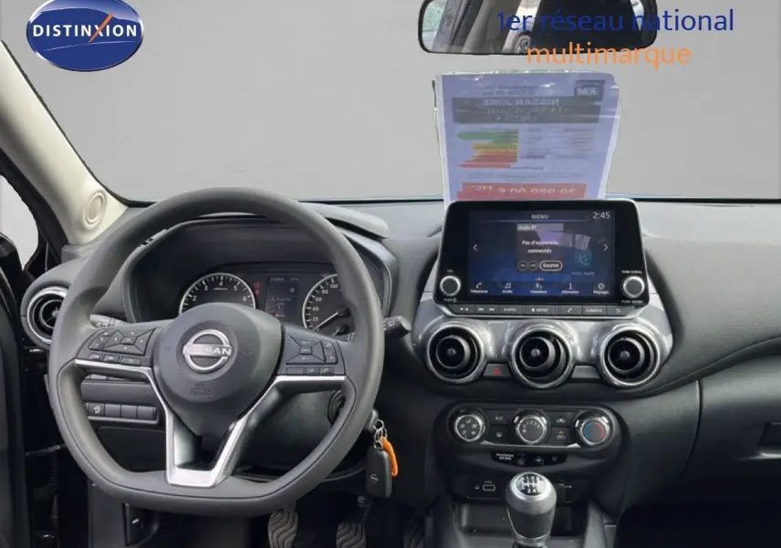 Vue intérieure frontale du tableau de bord noir du Nissan Juke 2023 avec volant multifonction et écran tactile central.