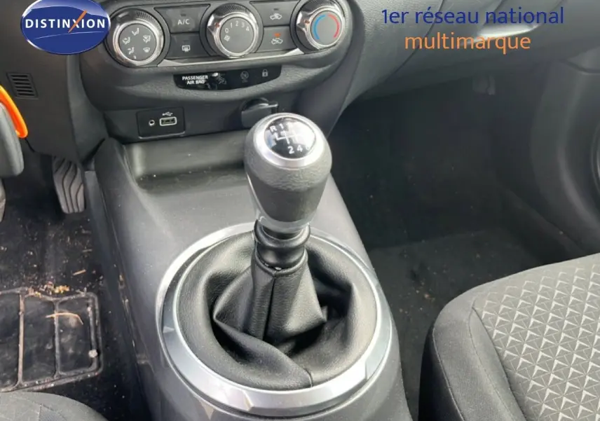 Gros plan sur la console centrale avec levier de vitesse manuel et commandes de climatisation d’un Nissan Juke noir.