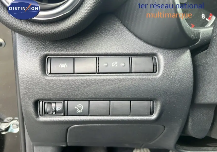 Gros plan sur les commandes de réglage d’éclairage et d’aide à la conduite du tableau de bord d’un Nissan Juke noir métal 2023.