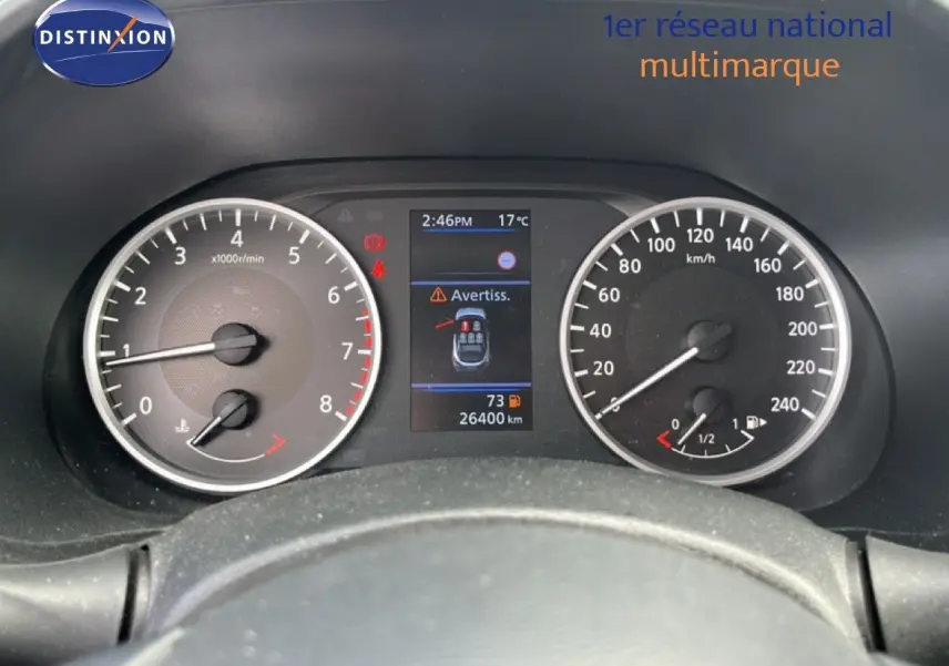 Vue rapprochée du tableau de bord noir du Nissan Juke 2023, avec compte-tours, vitesse et écran central d’alerte.