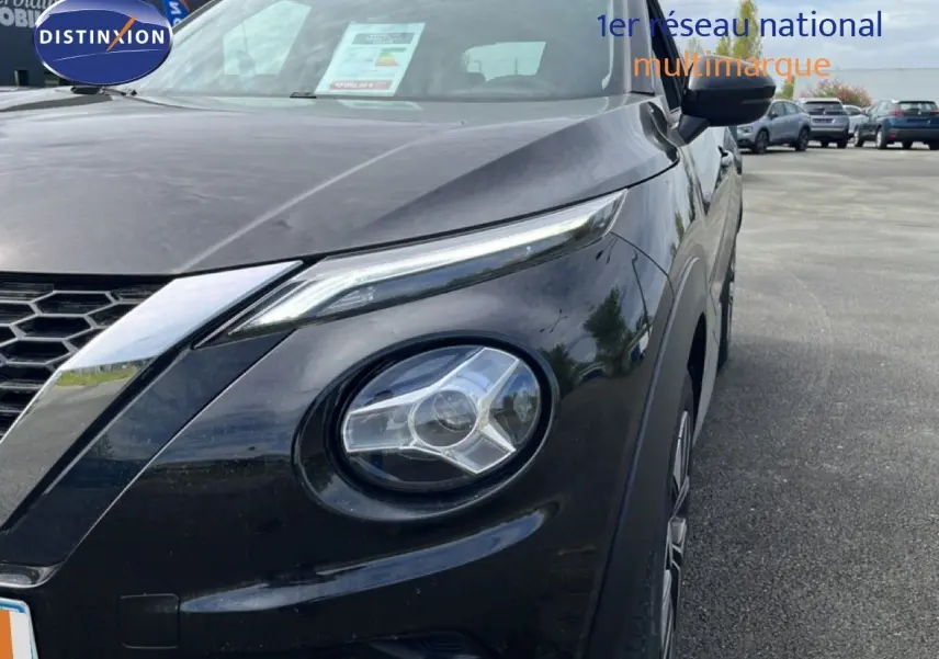 Vue 3/4 avant droit du Nissan Juke noir métal 2023, mettant en valeur ses phares ronds et sa calandre en nid d'abeille.