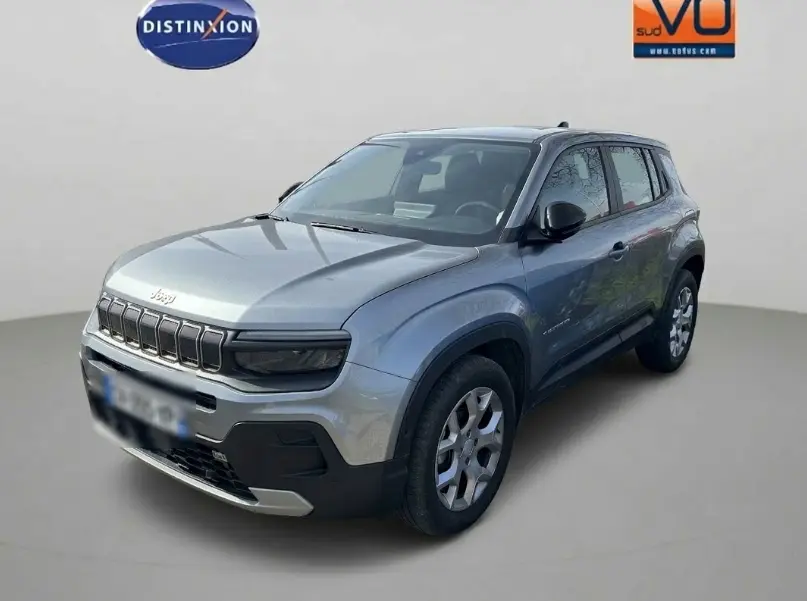 Jeep Avenger gris en 3/4 avant droit, avec calandre noire distinctive et jantes alliage 17 pouces visibles.