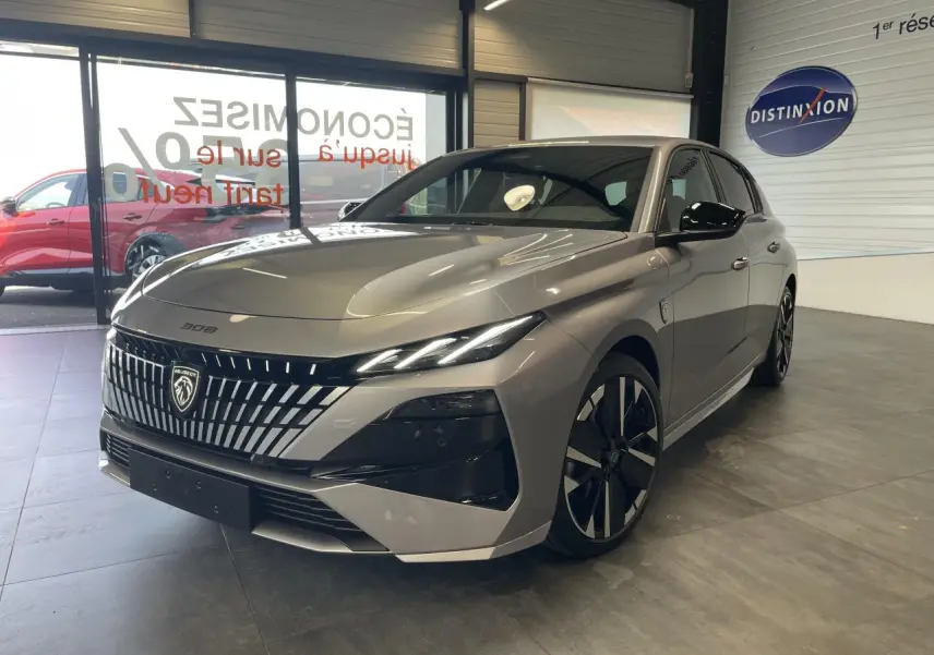 Peugeot 308 gris Artense vue 3/4 avant en intérieur, avec calandre distinctive et jantes alliage bi-tons.