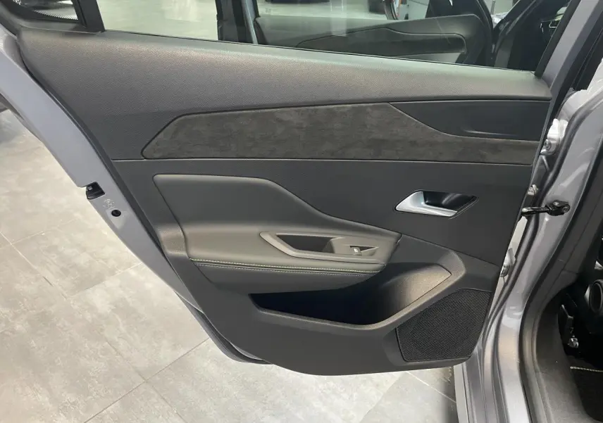 Porte arrière gauche ouverte d’une Peugeot 308 gris Artense, avec garniture noire et insert similicuir gris.