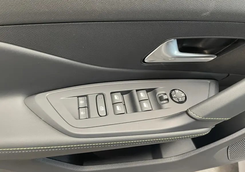 Gros plan sur la commande des vitres et rétroviseurs côté conducteur du Peugeot 308 gris Artense avec surpiqûres vert Adamite.