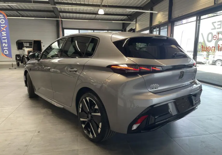 Peugeot 308 gris Artense vue 3/4 arrière droit en intérieur, avec feux arrière LED et jantes alliage bi-tons.