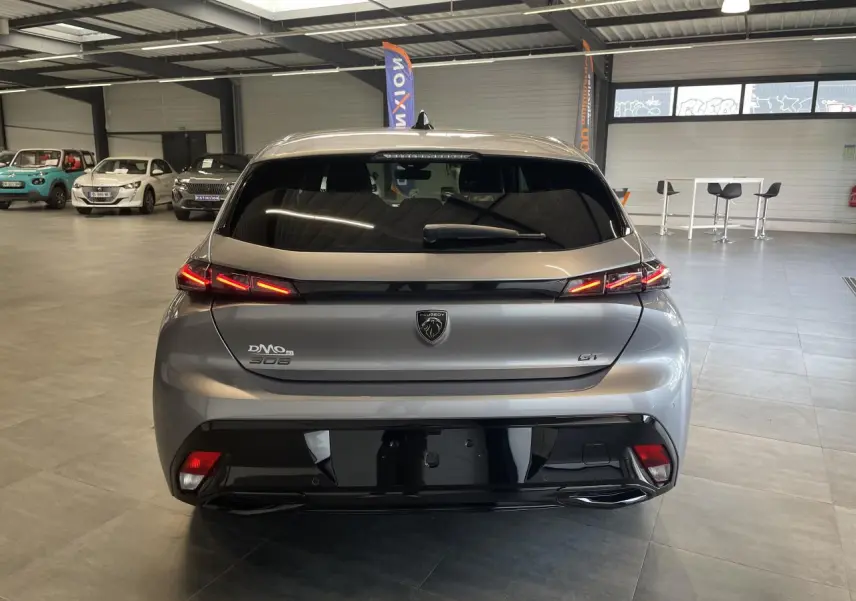Vue arrière d'une Peugeot 308 GT gris Artense avec feux arrière LED en forme de griffes et bandeau noir brillant.